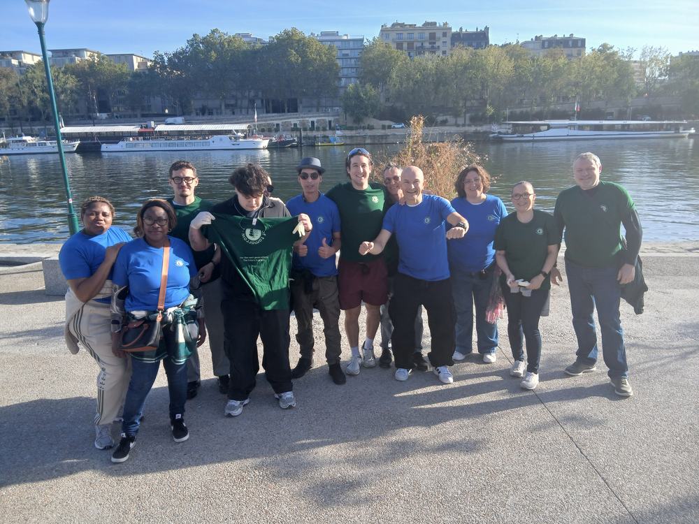 Thirteen volunteers in Creatives of Tomorrow T-shirts on the banks of the Seine on a sunny morning